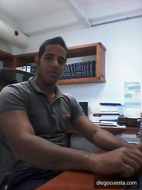 Diego Cuesta en su escritorio en Techno3, polo gris, librería con carpetas detrás