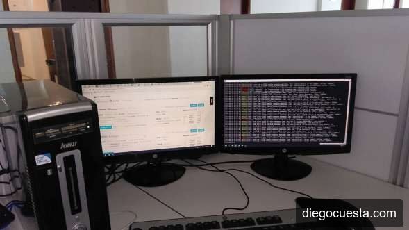 Estación de trabajo de notaría con dos monitores, uno mostrando interfaz web y otro una terminal